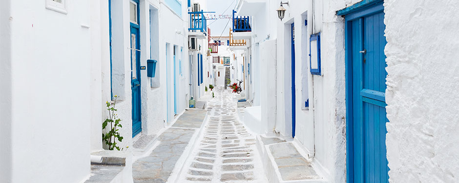 A whitewashed alleyway with blue doors in Mykonos